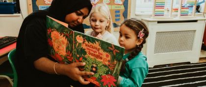 Storytime at Kindred Little Learners A practitioner reads a story to two children