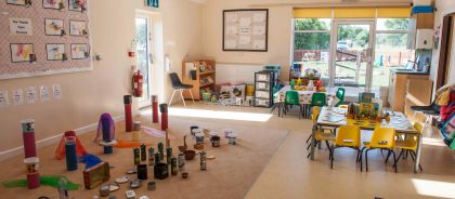 Kindred Huntingdon Nursery and Pre-School A bright, sunlit room at the nursery with low tables and chairs, an area for creative play, and displays of children's artwork on the wall.